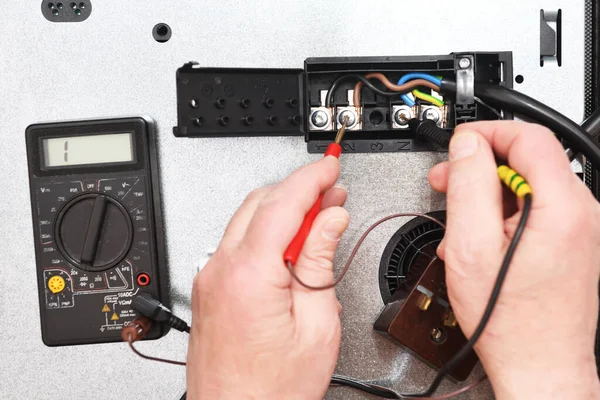 Profesyonel bir elektrikçi, yemek pişirme indüksiyon yüzeyindeki bağlantı kalitesini, bağlantıyı ve voltajı bir testçinin yardımıyla kontrol eder. Elektrikli ocakta sorun var..