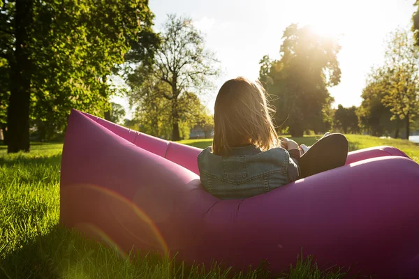 Mulher admira o pôr do sol em um sofá inflável — Fotografia de Stock