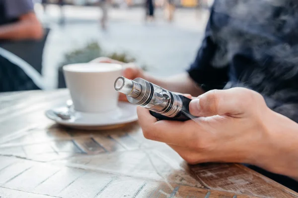 Hombre que usa vape o cigarrillo electrónico y bebe café — Foto de Stock