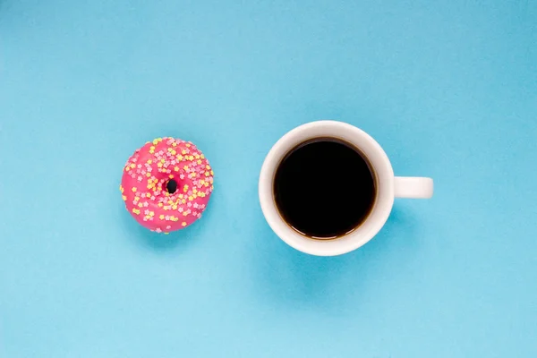 Donut rosa com xícara de café no fundo azul . — Fotografia de Stock