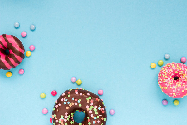 Sweet donuts with colorful candies on the blue background.