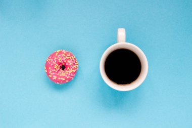 Mavi zemin üzerine kahve ile pembe çörek.