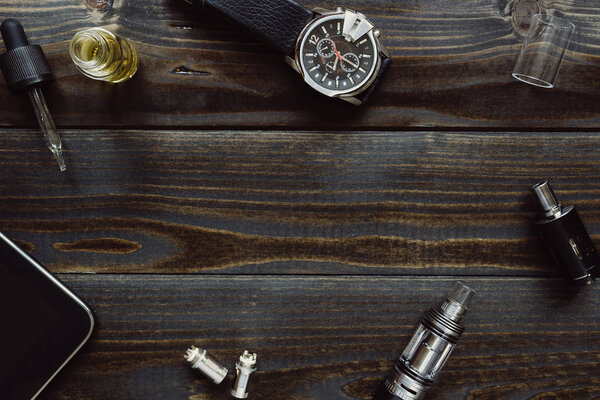 Vaping set, watch and tablet on the dark table. Hipster or bussinesman style.