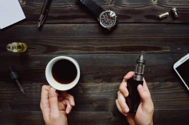 Vape veya elektronik sigara sigara ve kahve içme adam. Vi