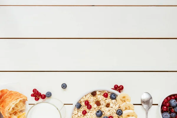 Gezond ontbijt met croissant, bessen en melk op de witte houten tafel met kopie ruimte, bovenaanzicht — Stockfoto