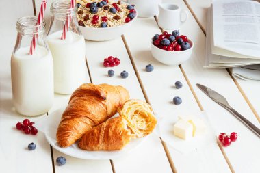 Lezzetli kahvaltı kruvasan, yulaf gevreği, çilek ve süt beyaz ahşap tablo