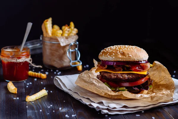 Świeże, pyszne Burgery z frytkami, sos na drewnianym stole — Zdjęcie stockowe