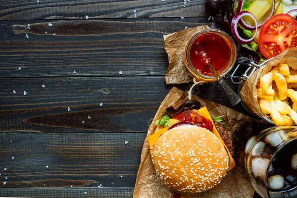 Świeże pyszne hamburgery, frytki, sos i pić na widok drewniany blat, z miejsca kopii — Zdjęcie stockowe