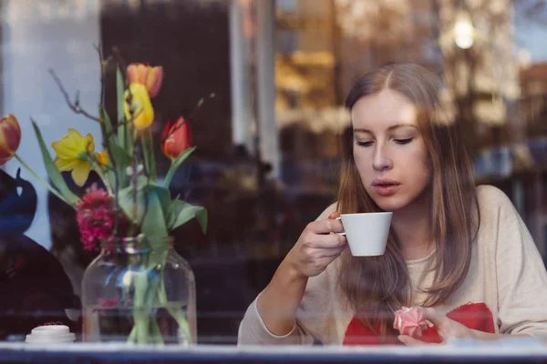 Hermosa joven bebiendo café en la cafetería cerca de la ventana —  Fotos de Stock