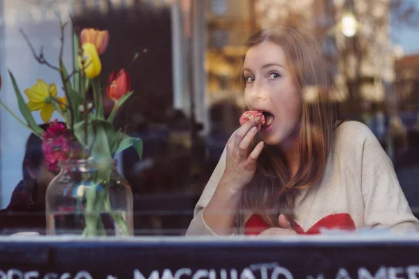 Hermosa mujer divertida comiendo postre y tomando café en la cafetería cerca de la ventana —  Fotos de Stock