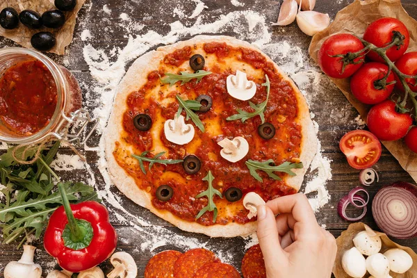Pizza yemek. Pizza için maddeler ekleyerek eller. Pizza ingerdients tahta masada, üstten görünüm