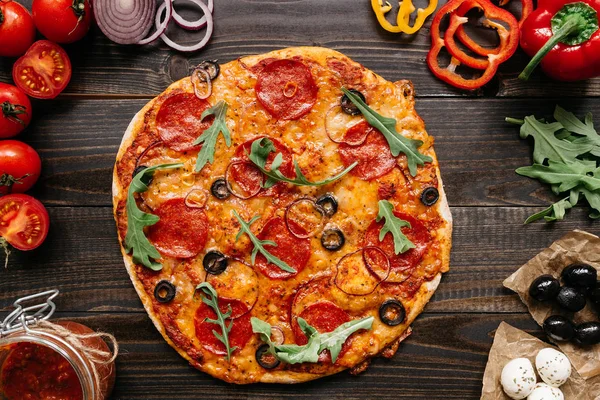 Pizza deliciosa fresca con ingredientes de pizza en la mesa de madera, vista superior — Foto de Stock
