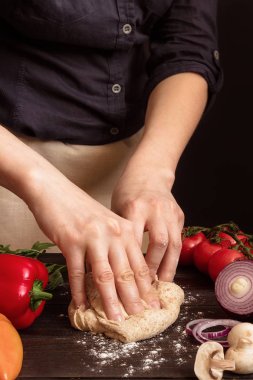 Kadın hamur pizza yemeye hazırlanıyor. Ahşap masa üzerinde hamur yoğurma eller