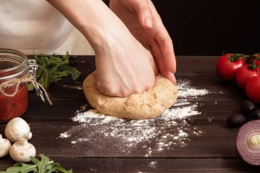 Kadın hamur pizza yemeye hazırlanıyor. Ahşap masa üzerinde hamur yoğurma eller