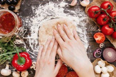 Kadın hamur pizza yemeye hazırlanıyor. Ahşap masa, üstten görünüm üzerinde hamur yoğurma eller