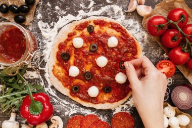 Pizza yemek. Pizza için maddeler ekleyerek eller. Pizza ingerdients tahta masada, üstten görünüm