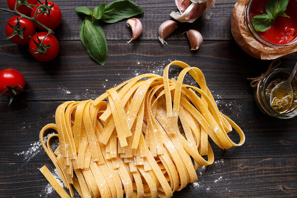 Fresh homemade pasta and vegetables on the dark wooden table top view