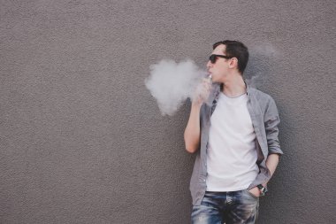 Genç yasaktır, vaping elektronik sigara veya vape adam. Gri arka planı