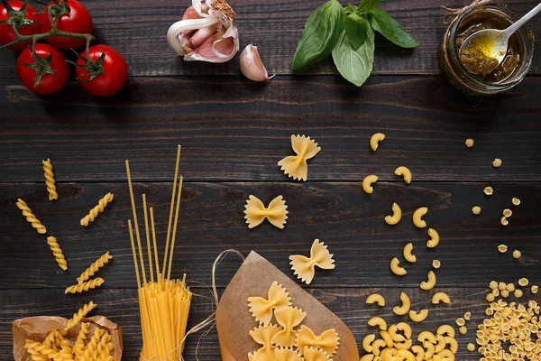 Dried mixed pasta and vegetables on the dark wooden table top view — Stock Photo, Image