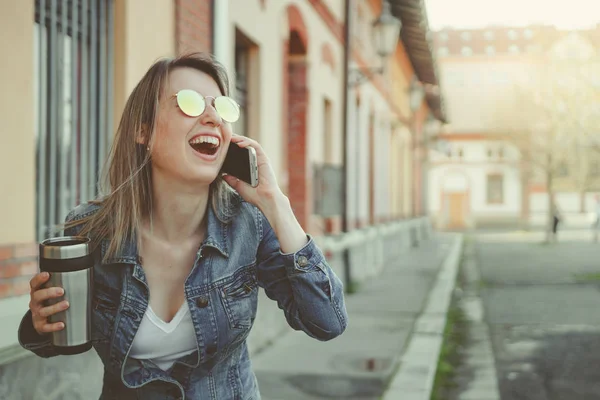 Feliz jovem hipster mulher andando na rua, usando seu smartphone e beber café — Fotografia de Stock