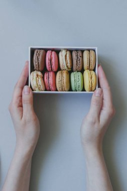 Hediye kutusu açık mavi renkli, üstten görünüm üzerinde lezzetli macaroons ile holding eller