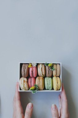Hediye kutusu açık mavi renkli, üstten görünüm üzerinde lezzetli macaroons ile holding eller