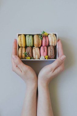 Hediye kutusu açık mavi renkli, üstten görünüm üzerinde lezzetli macaroons ile holding eller
