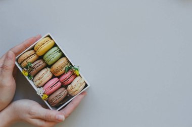Hediye kutusu açık mavi renkli, üstten görünüm üzerinde lezzetli macaroons ile holding eller