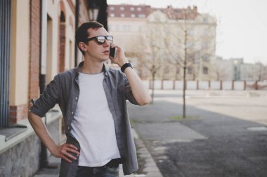 Sokakta yürüyen ve kopya alanı ile telefonda konuşurken mutlu genç hipster adam