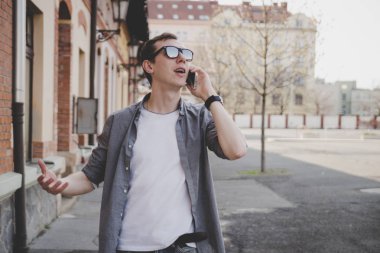 Sokakta yürüyen ve kopya alanı ile telefonda konuşurken mutlu genç hipster adam