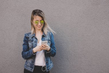 Akıllı telefon kullanan genç mutlu çekici kadın. Gri arka plan, kopya alanı