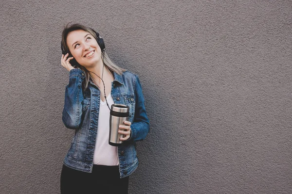 Jovem mulher atraente ouvir música e beber café. fundo cinza, espaço de cópia — Fotografia de Stock