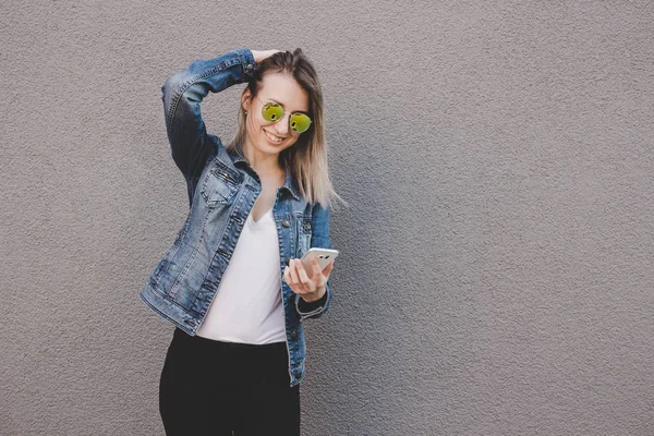 Jovem mulher atraente feliz usando telefone inteligente. fundo cinza, espaço de cópia — Fotografia de Stock