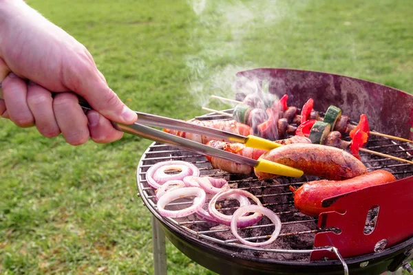 Homem cozinhar na grelha com vários deliciosos churrasco ao ar livre, foco seletivo — Fotografia de Stock