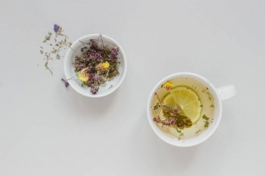 Çay saati. Fincan sıcak bitkisel çay ve kuru çay gri arka planda, üstten görünüm