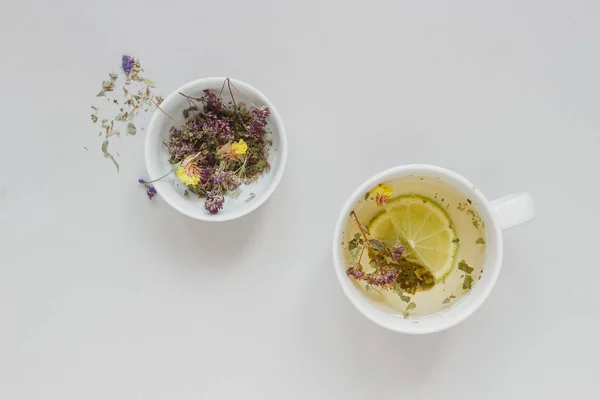 Hora del té. Taza de té caliente de hierbas y té seco en el fondo gris, vista superior — Foto de Stock