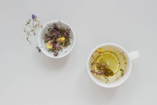 Tea time. Cup of hot herbal tea and dry tea on the gray background, top view