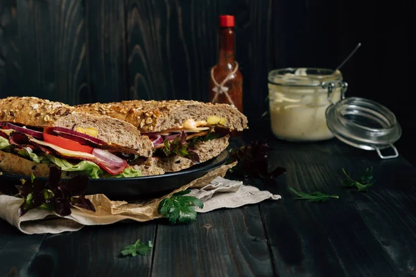 Свіжий смачний бутерброд підводних човнів і соуси на дерев'яному темному столі — стокове фото