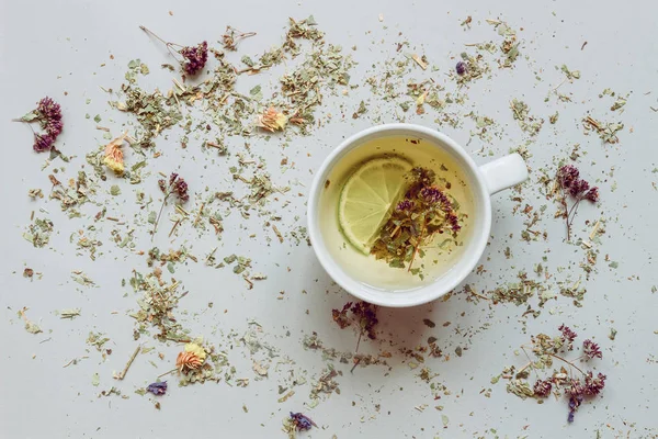 Tea background. Dry herbal tea and cup of hot tea on the gray background. Copy space