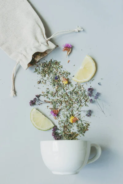 Tedags. Torra örtte och cup på den grå bakgrunden, ovanifrån — Stockfoto