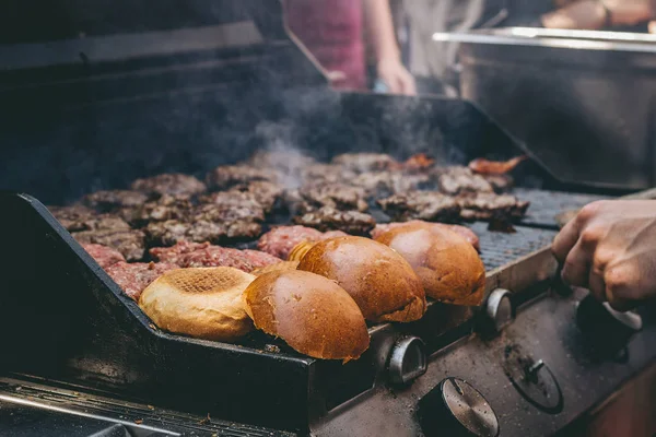 Cucina deliziosi hamburger di carne succosi e panini alla griglia — Foto Stock