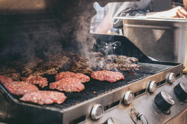 Cucinare deliziosi hamburger di carne succosi sulla griglia all'aperto — Foto Stock