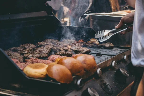 Cottura deliziosi hamburger di carne succosa e panini sulla griglia all'aperto . — Foto Stock