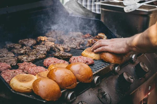 Готовить вкусные сочные мясные бургеры и булочки на гриле на открытом воздухе . — стоковое фото