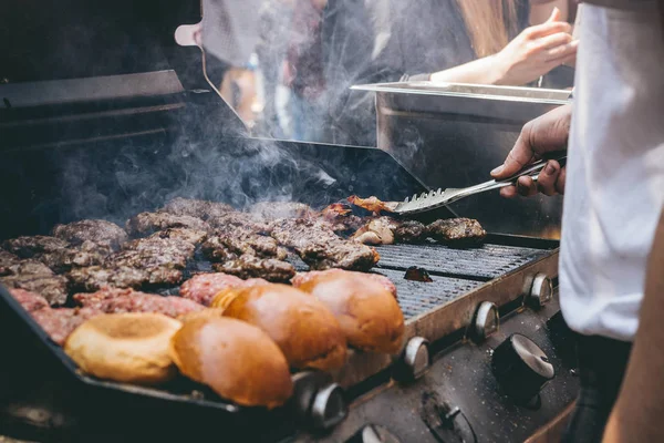 Cozinhar deliciosos hambúrgueres de carne suculentos e pães na grelha — Fotografia de Stock