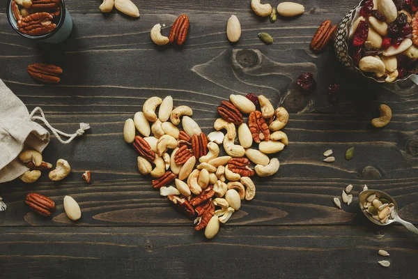 ハート型木製テーブルの上にナッツを混ぜます。種子と木製のテーブルにドライ フルーツとナッツ ミックス — ストック写真