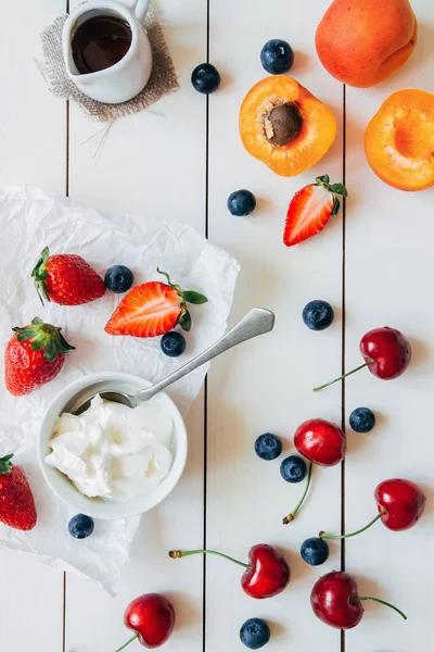 Frutas de verano. Bayas jugosas frescas y albaricoque en la mesa de madera blanca, vista superior — Foto de Stock