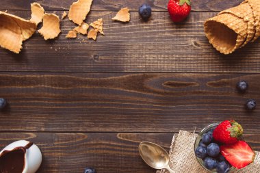 taze çilek, gözleme koni ve ahşap zemin üzerine çikolata sosu görünümü top. Dondurma arka plan kopya alanı ile