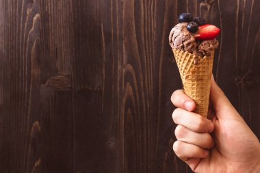 Çikolatalı dondurma çilek ile ahşap arka plan üzerinde tutan eller