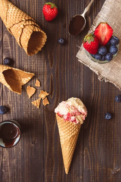 Ice-cream with fresh berries and chocolate sauce on the wooden background, top view — Stock Photo, Image